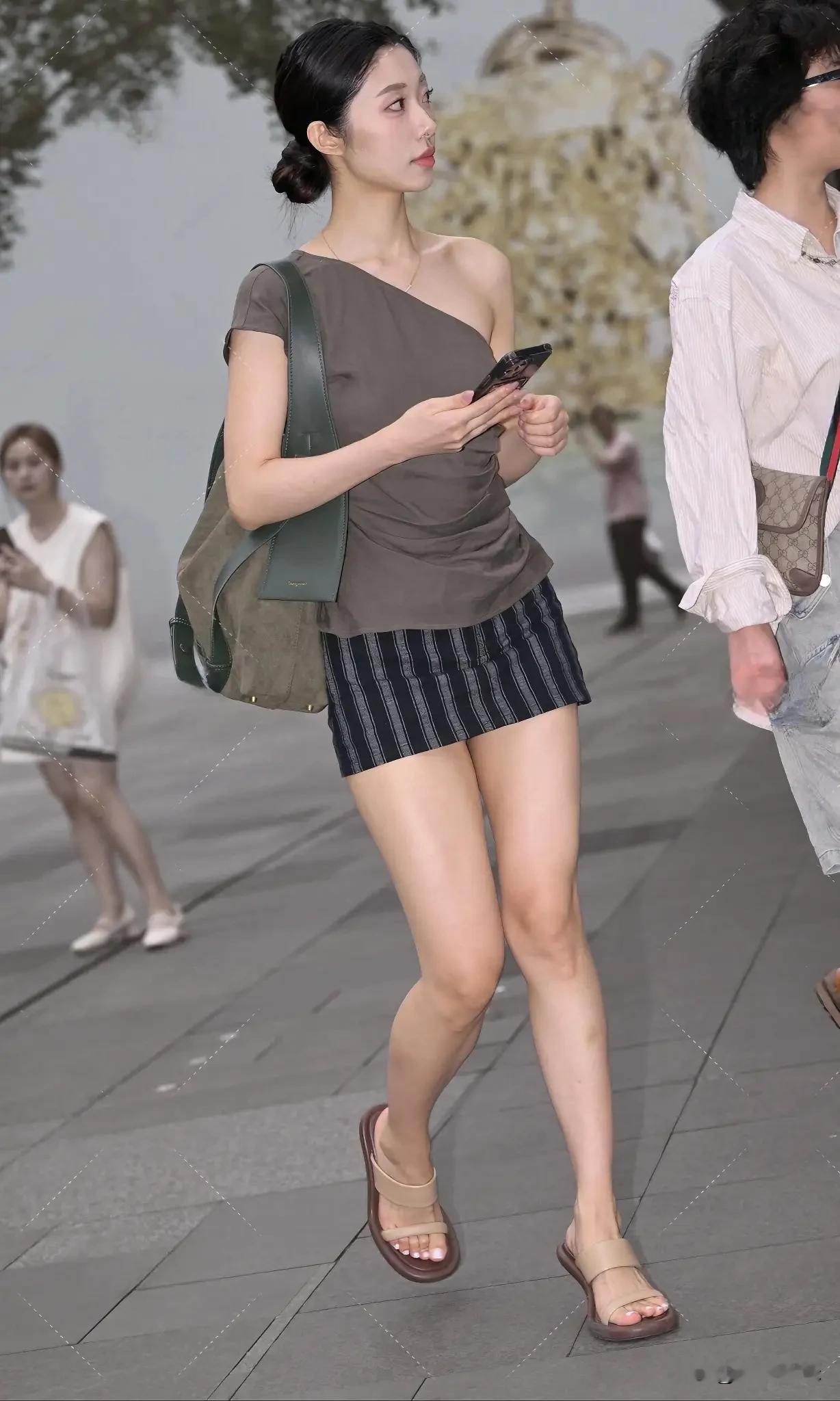 都市时尚少女，条纹短裙搭配绿包，轻松漫步街头