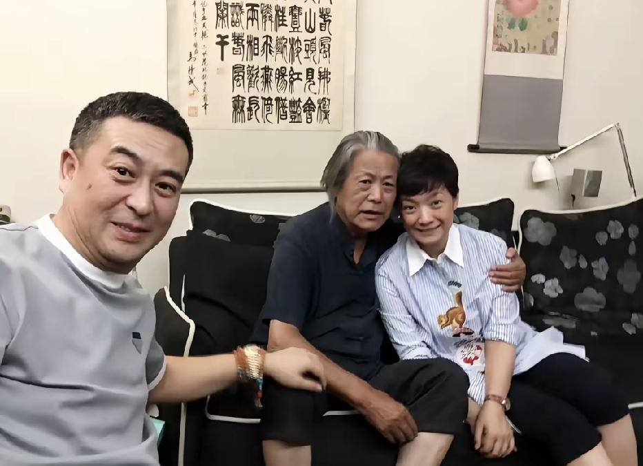 这张居家合影，左为演员张嘉益，中间是他的恩师马精武，右侧是张嘉益妻子王海燕。马精武是北电资深教授，桃李满天下，张嘉益当年便受其悉心教导。夫妻二人登门探望老师，屋内墨香萦绕，氛围温馨。一张照片，藏着师徒多年深厚情谊，见证演艺行业薪火相传。