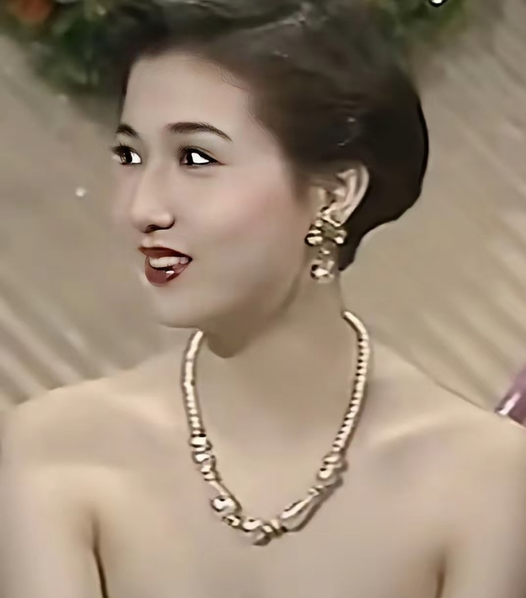 成龙的前女友吴绮莉，她此时才17岁，梳着一头短发，身穿白色抹胸礼裙，甜美又英气，一颦一笑自带风情 ​