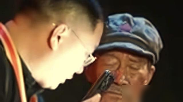 李雪健双耳彻底失聪，却还在台上演红军炊事班长。
10月22日央视长征晚会，他提一盏马灯出场，没一句台词，没一个对手。总导演于蕾说，彩排全靠写字沟通，节目里的声音是AI生成的。
因为2000年那场鼻咽癌，放化疗把他唾液腺打坏了，声带也毁了。人民日报上个月专访确认，常规助听器对他已经没用，日常得靠语
