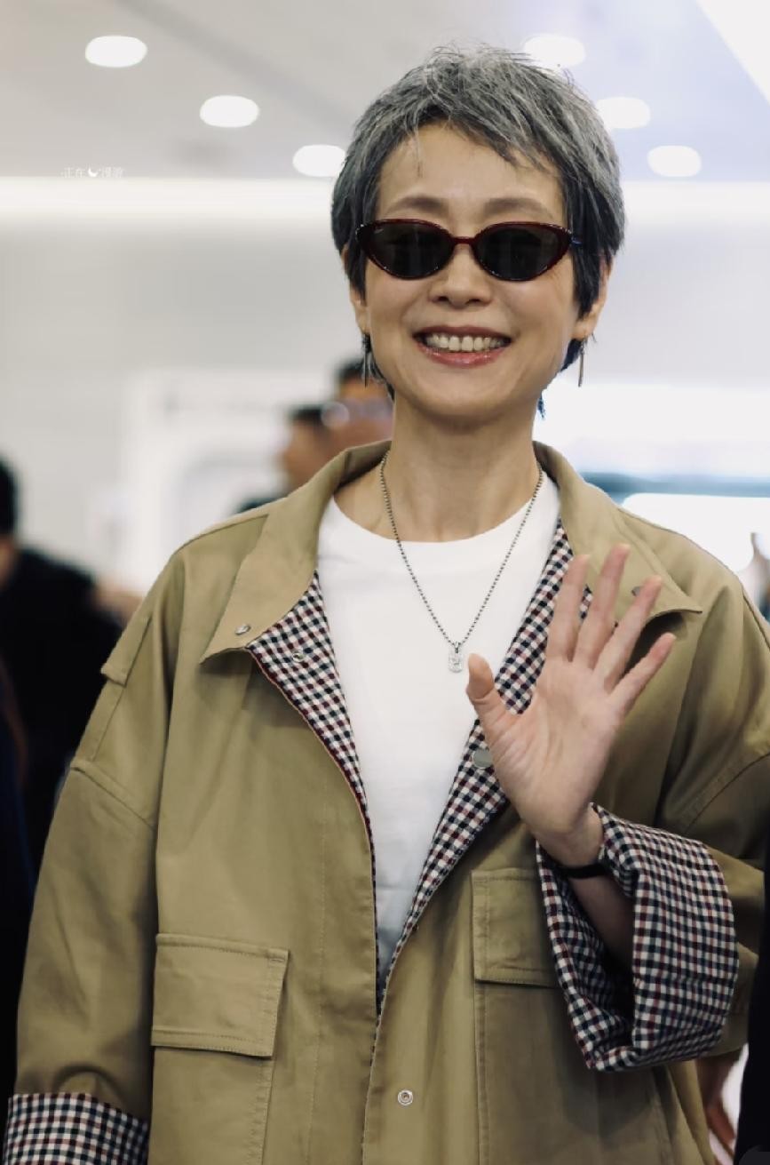 60多岁的叶童在机场一露面，直接撕下了多少人“不敢变老、拼命装嫩”的遮羞布。
满头银白头发完全不染，戴副黑超墨镜，一身宽宽松松的低饱和度卡其工装，连袖口卷起来露出的格纹都透着漫不经心。
很多上了年纪的人穿衣服特别容易走两个极端，要么把自己往花花绿绿的“大妈碎花”里套，要么就拼命医美、染黑发去够年
