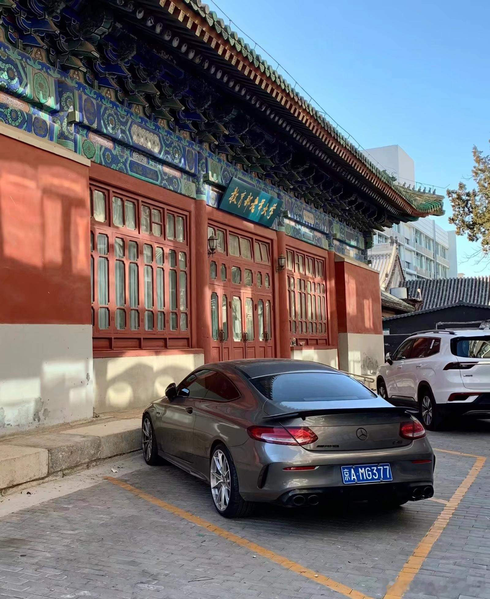 🚗 奔驰AMG C63 轿跑车实拍
📋 车辆基础信息
‌车辆型号‌：奔驰 AMG C63 双门轿跑车
‌车身配色‌：哑光金属灰
‌车牌属地‌：京A 北京号牌，完整号牌为 京A·MG377
‌核心特征‌：搭载大排量V8动力，配备标志性的四出圆形排气、专属AMG运动尾翼以及多辐式运动轮毂。

🏛️ 场景环境信息
画面背 ​