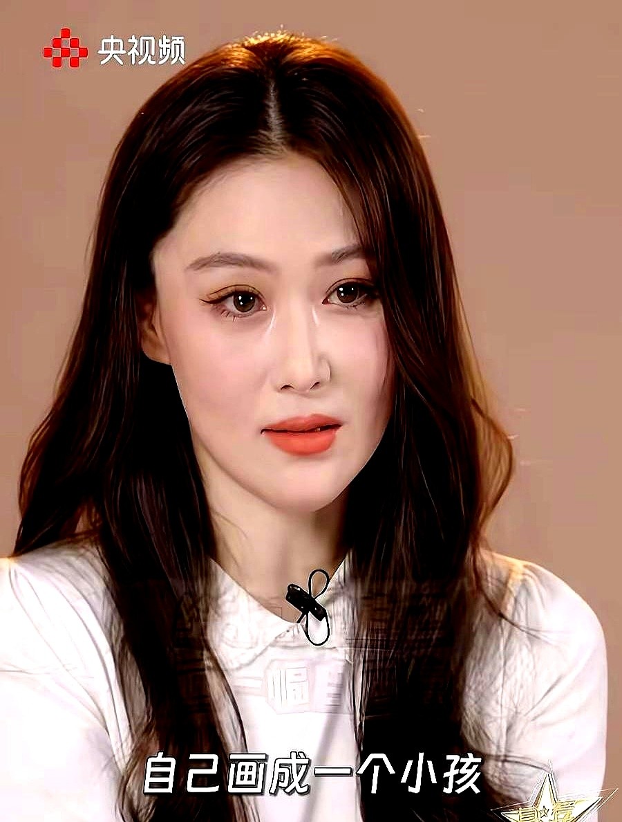 张馨予穿着白上衣，翘着腿坐在椅子上，眼眶泛红。

以前在娱乐圈摸爬滚打的时候，她虽然漂亮，但眉眼间总带着点凌厉的攻击性，像是在名利场里争得头破血流。

但这次在央媒采访里露面，感觉变了。

她现在下巴圆润了些，五官卸下了防备。自从嫁了人，在自家小院里种菜画画，心里的算计和委屈少了，整个人自然就舒展了