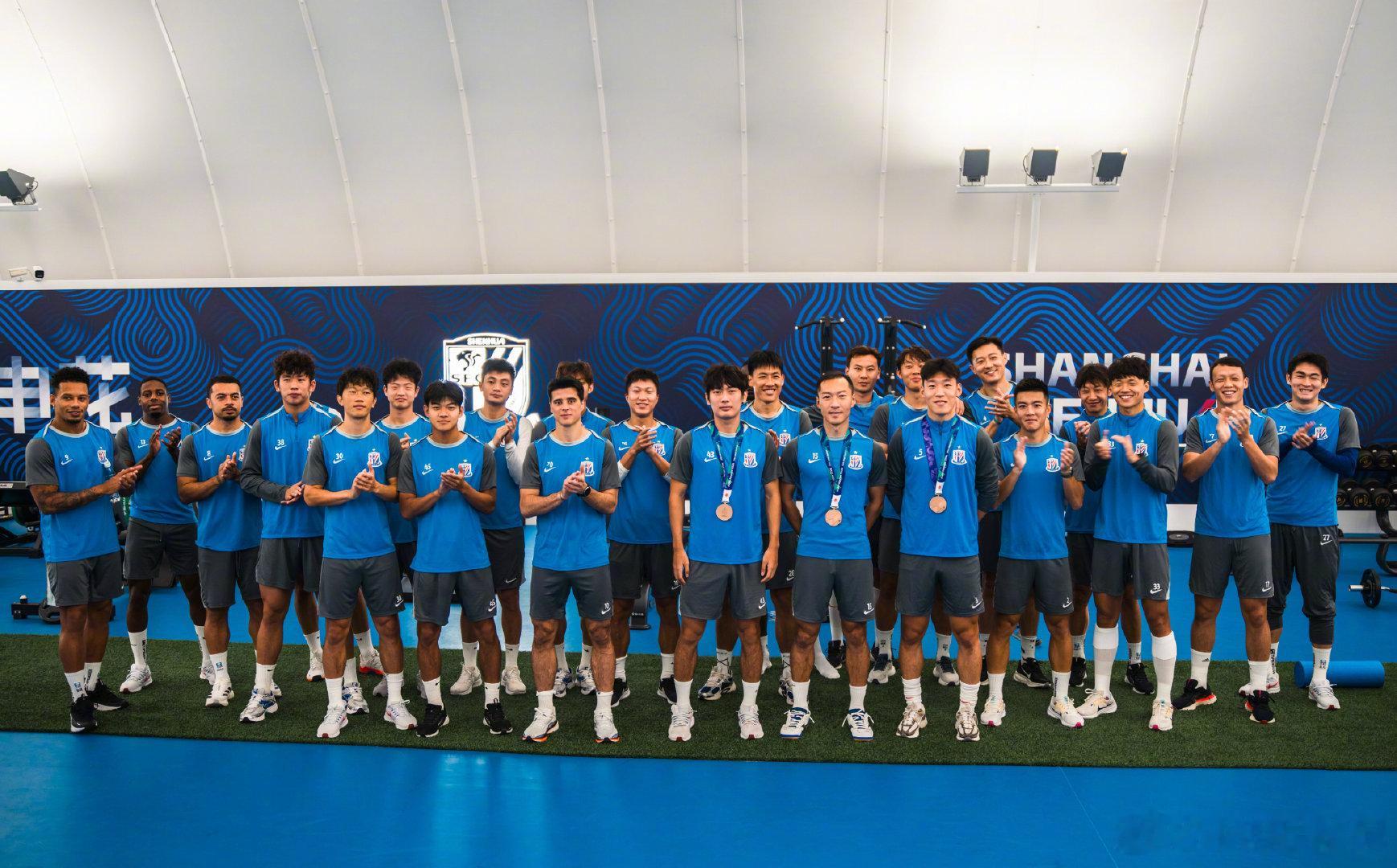 上海申花俱乐部今天在社媒晒图，全队合影欢迎三名亚运男足队员载誉归来。申花方面贡献了吴曦、朱辰杰和杨皓宇三名球员。 ​