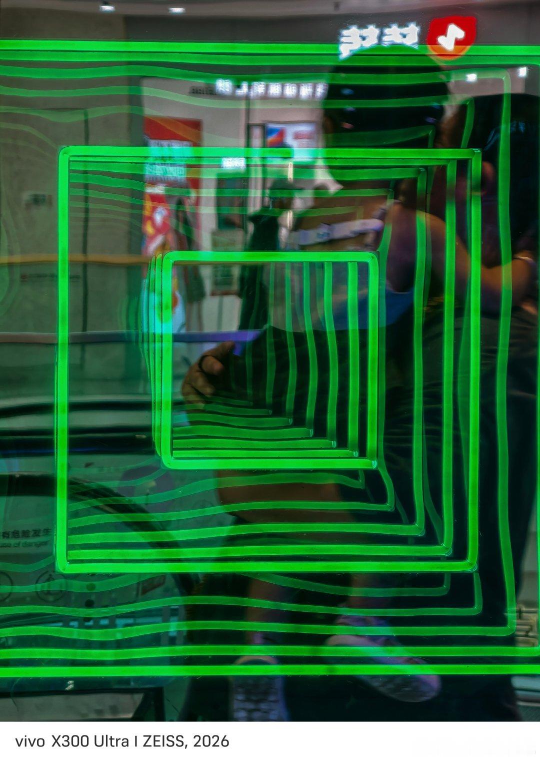 #vivo[超话]# 霓虹几何，都市光影幻境#人间回响# 
商场里的绿色霓虹层层嵌套，方形线条扭曲流转，玻璃倒影里藏着行人身影。流动的光纹勾勒出赛博氛围感，日常市井被霓虹赋予别样奇幻质感，定格都市里偶然遇见的视觉趣味。
vivo X300 Ultra#2026V粉嘉年华##vivo相册里的高光时刻##微博影像年##vivo超话##vivox300ultra专业v单#