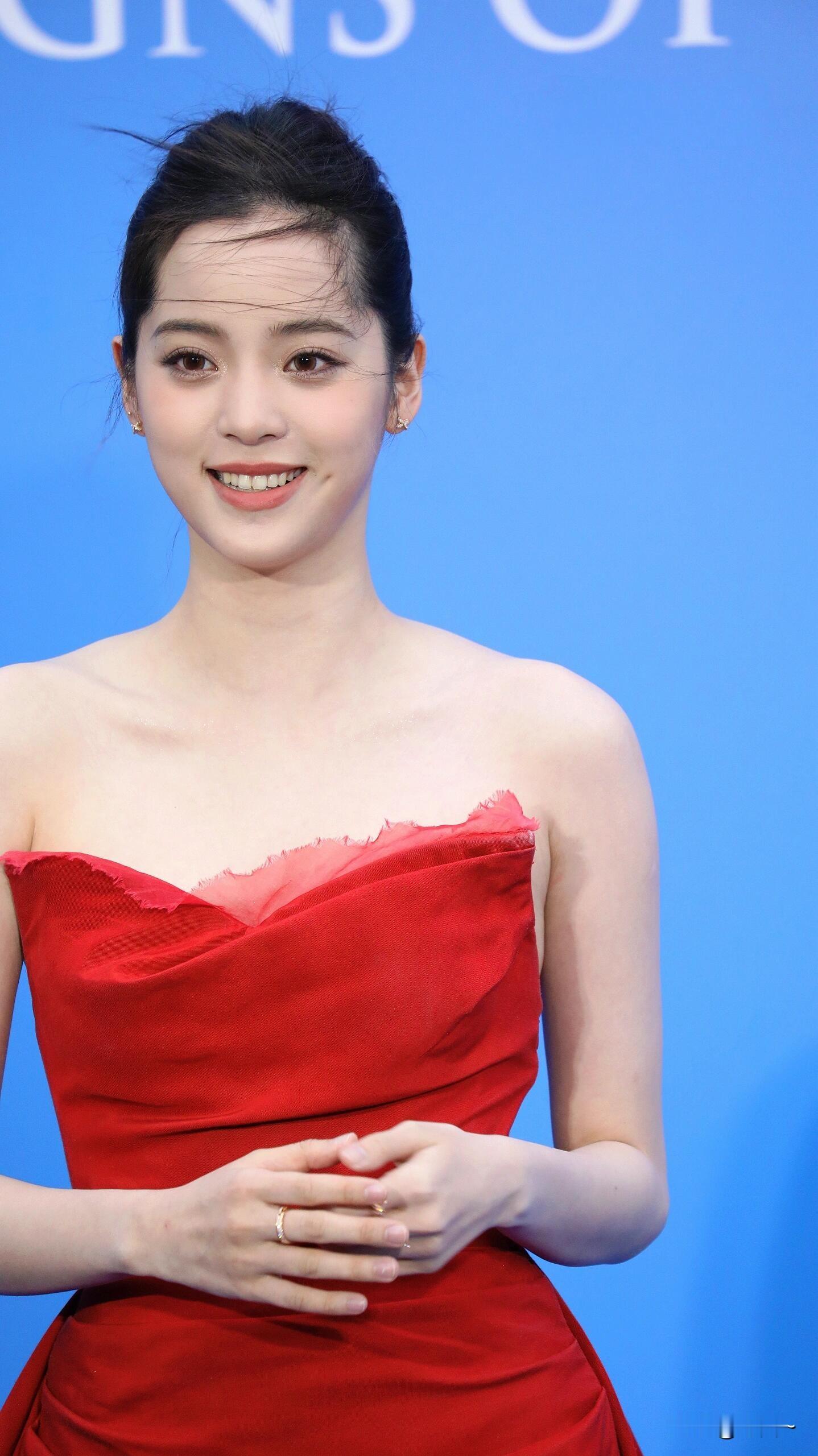 欧阳娜娜身穿红色抹胸裙，笑容甜美治愈，举手投足间尽显灵动优雅。欧阳娜娜