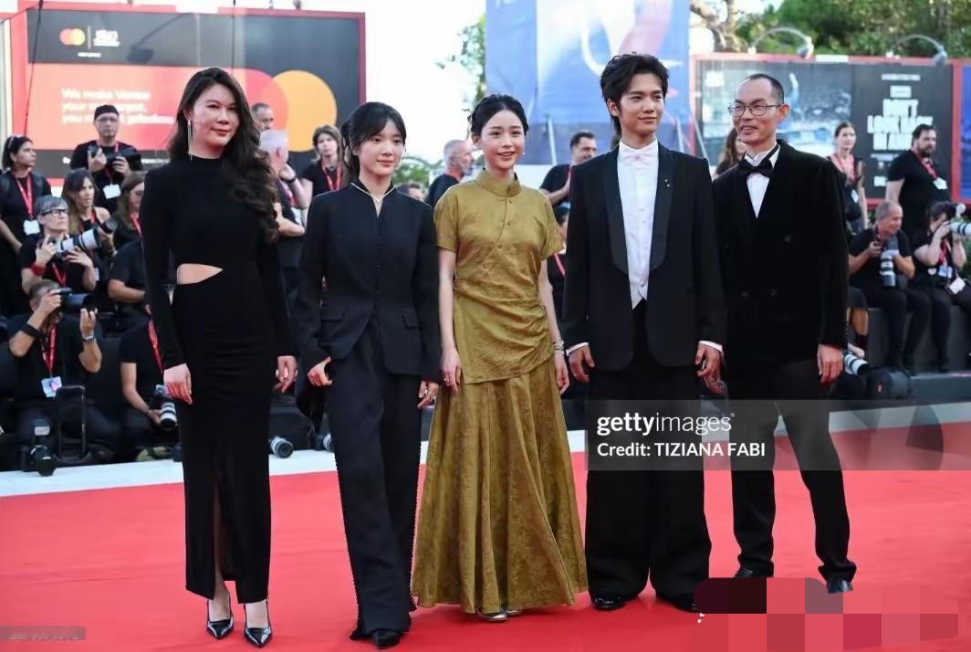 阿嬷剧组威尼斯走红毯，主演们脸好小，尤其是女主穿金色改良旗袍，戴着温润的玉镯，盘起来头发，梨涡浅笑的样子尽显东方美韵。
木生南枝一旁守护，都穿了黑西装，气场特别强。
这个阵容，真是让人连连称赞！
当导演蓝鸿春、主演王彦桐、王晓慧、李思潼，还有制片人郑萱轩齐刷刷走上国际红毯，真是把“意气风发”四个字具