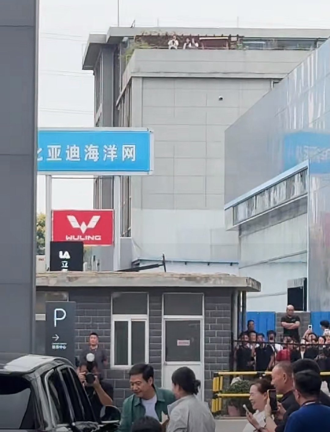 雷总又在给澎程车主交车，又开门又合影，女车主直接咔咔咔自拍合影，真的太值了。然后连附近的楼顶都站满了人！ （雷军为澎程车主开车门） ​