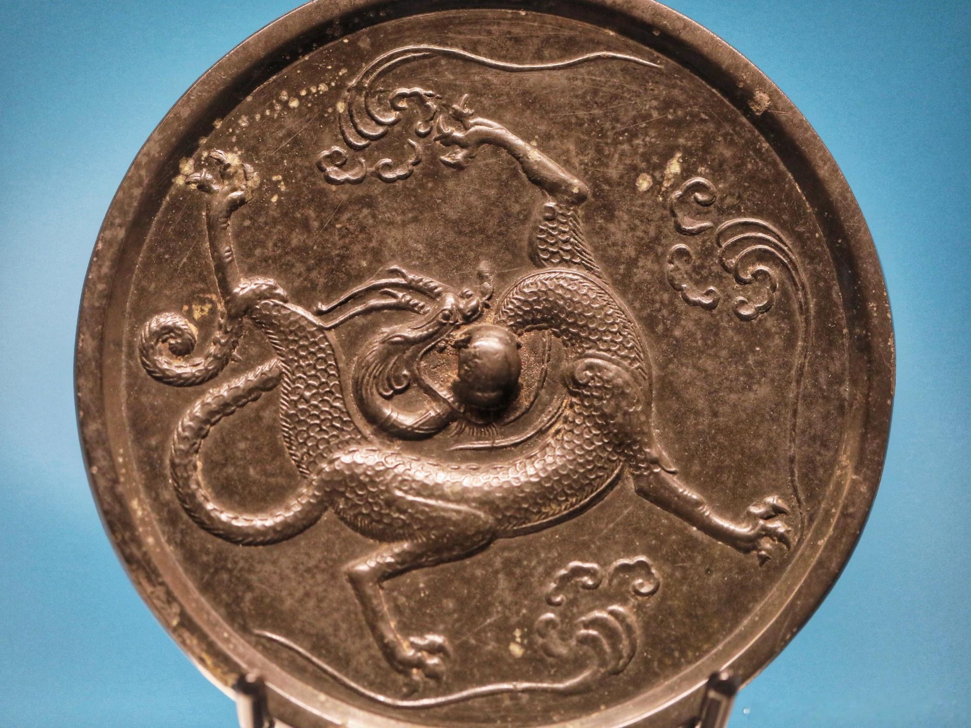 唐 盘龙纹铜镜扬州博物馆藏镜作圆形，设圆钮，窄平素缘。钮外三朵流云之间...