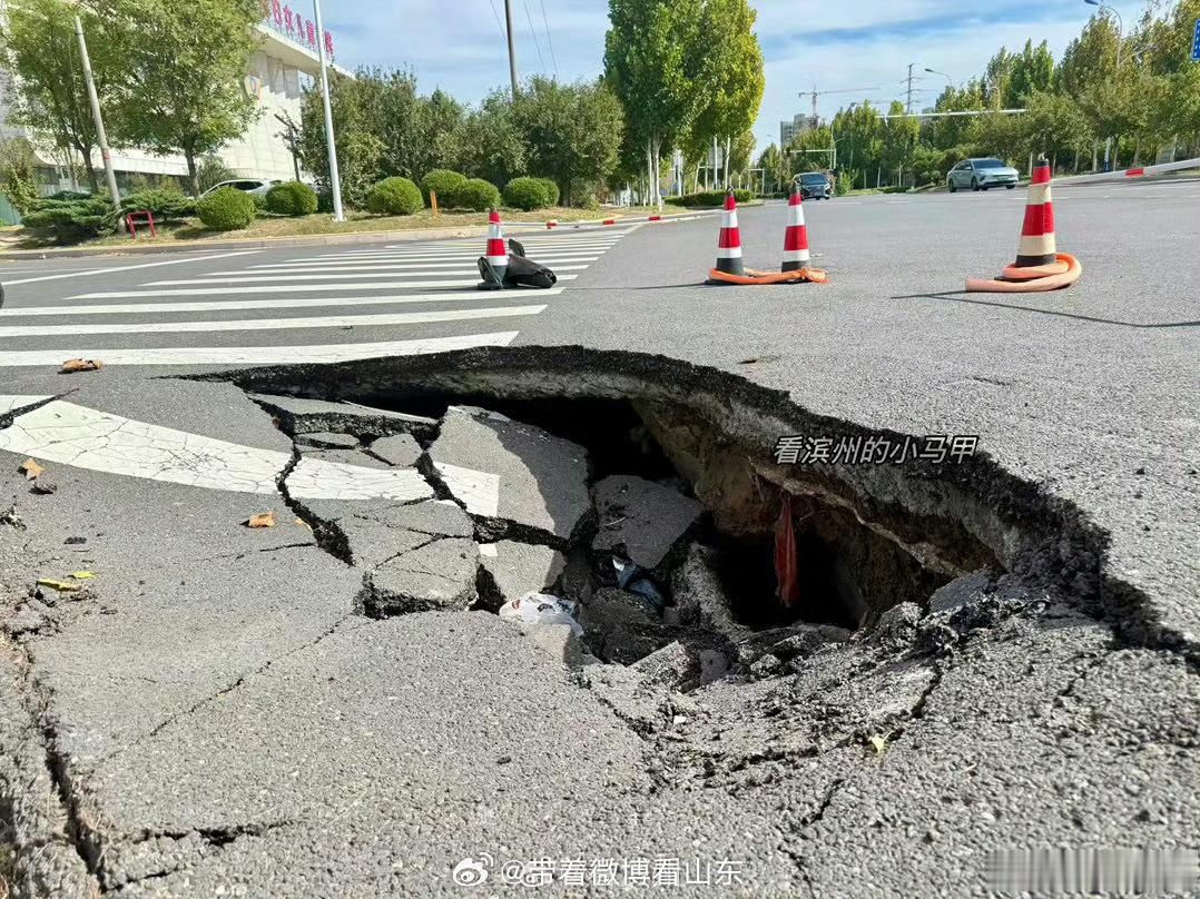 【滨州一路面被渣土车压塌 本身质量问题还是渣土车太重所致？】近日，山东滨州，黄河十五路、渤海十八路路口，市人民医院附近路面突发塌陷。大坑位于路口转角处，所幸不在直行主车道，交警第一时间到场维持秩序，周边紧急布设警示设施，事件未造成人员伤亡与严重通行事故。事发后不少人下意识归咎于现场的渣土车太重，仿佛塌陷全是重载车辆的锅。可照这个逻辑，踩断刹车踏板该怪脚力太大，绷断琴弦该怪手指太使劲，横竖都是使用者的错，东西本身永远没问题？事实上塌陷处下方早已被管线渗漏冲刷掏空，路基虚浮、内里空洞，路面早就成了 “空心路”。路的本分就是承重，只盯着表面柏油、怪罪路过车辆，却不肯正视地下工程的质量隐患，纯属本末倒置。城市道路安全不能只做表面文章，地下隐患排查才是真正的良心工程。 滨州