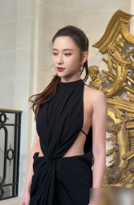 何超莲那条黑裙子，吊牌没摘就出门了。
在巴黎RV的活动上，镜头怼过去，领口那根白色标签晃得刺眼。网友第一反应：这衣服是不是借的，拍完还得还回去。她倒没慌，照样跟娜然、设计师站一块儿合影，笑得挺开。
35岁了，生图里眼角有点疲态，踩着细高跟走路也收着劲儿。旁边娜然个高腿长，往那一站，像来拍大片的，