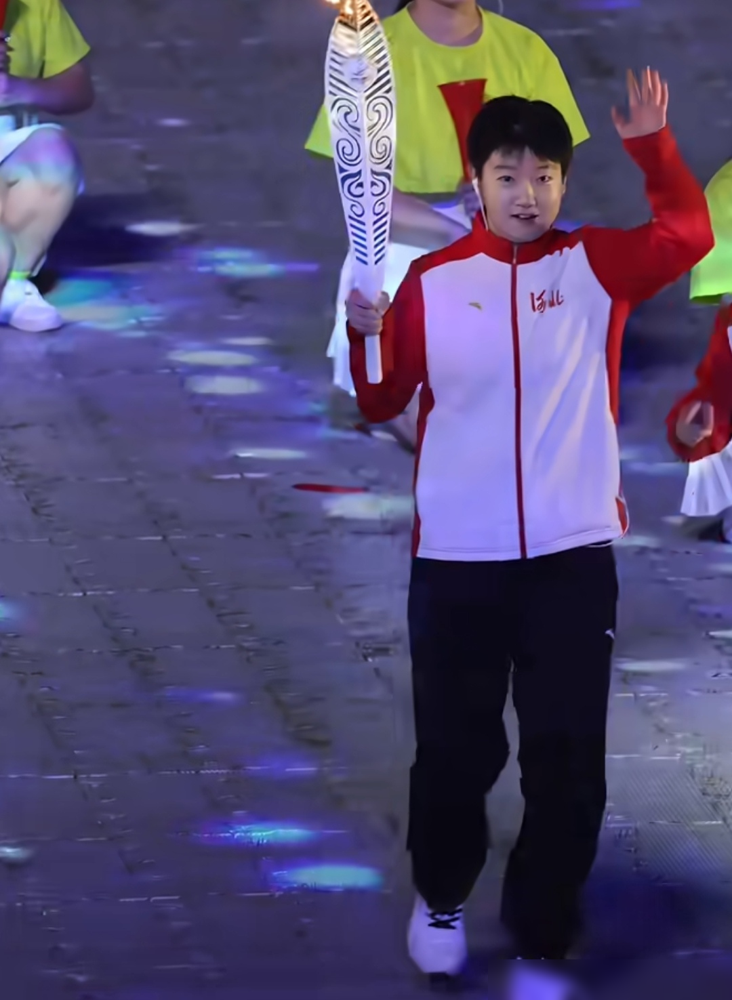孙颖莎跑错位了，还差点把引路小孩也带偏。
10月16号晚，河北省第十七届运动会开幕式，莎莎是第六棒火炬手，搭档一个11岁的省冠军小姑娘。到圣火展示区，两人站位偏了，半截身子都在阴影里。
小孩先发现不对，莎莎也反应过来了。
结果她没慌，举着火把，侧着身，小碎步一点一点往光圈中心挪，跟走螃蟹步似的