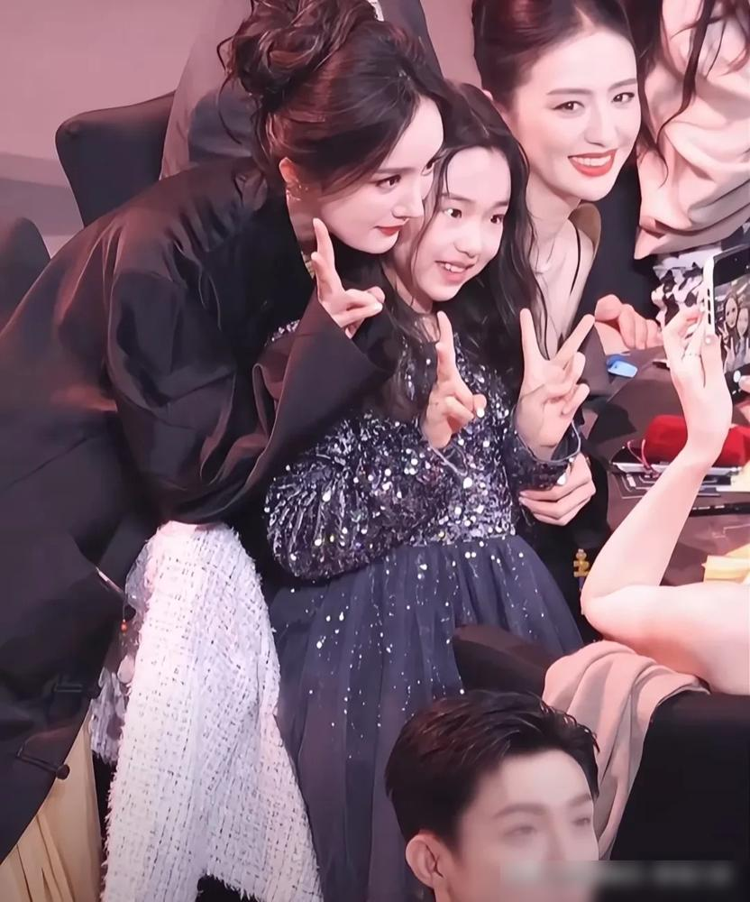 杨幂穿着几万的高定，弯着腰在那鬼鬼祟祟找角度，就为了跟一个小姑娘贴脸合影。
拍完还嫌董璇手不稳，直接喊工作人员过来重拍。
这小姑娘叫小酒窝，董璇闺女。
杨丽萍手把手教过她孔雀舞，周也探班抱着她不撒手，还专门送发圈哄着玩。
转头小酒窝就进组了，客串周也小时候，戏里戏外都连上了。
再往下挖，杨