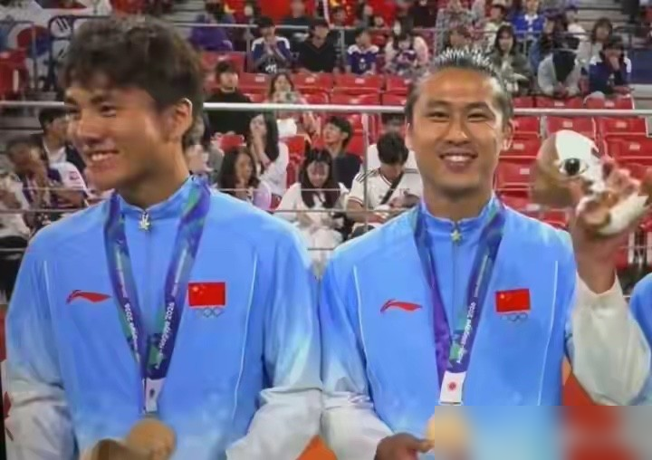 国足拿块铜牌，全队跟夺冠似的在更衣室跳手势舞，王钰栋咬着牌子自拍，吴曦发动态说答应你们的事分你们一半。回北京那天，几百号人堵在T3喊中国队牛。反观国乒男团，决赛输给日本拿了银牌，领奖台上一个个跟坐钉板似的，牌子摘下来攥手里，脸黑得能拧出水。球迷那边更绝，评论区全是丢人下课。都是国字号，一个第28年才