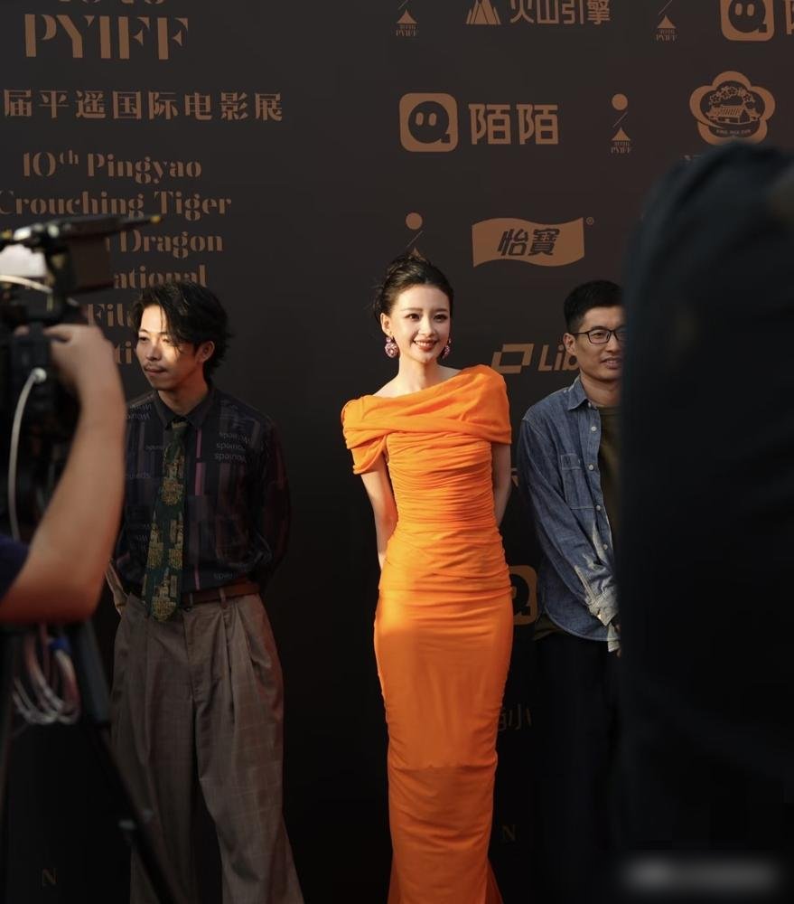 孙怡穿着巴黎世家2026秋季亮橘色露背裙站上平遥红毯，转身就拿了费穆荣誉最佳女演员。这反差，太狠了。
电影《爱情笑话》里她演“小美”，素颜，糙得掉渣，跟红毯上那个露背亮橘完全是两个人。领奖时她说，这奖让她有信心继续演电影。
转头上了《你好星期六》，游戏输了给工作人员发月饼，还专挑摄像机位发。热搜