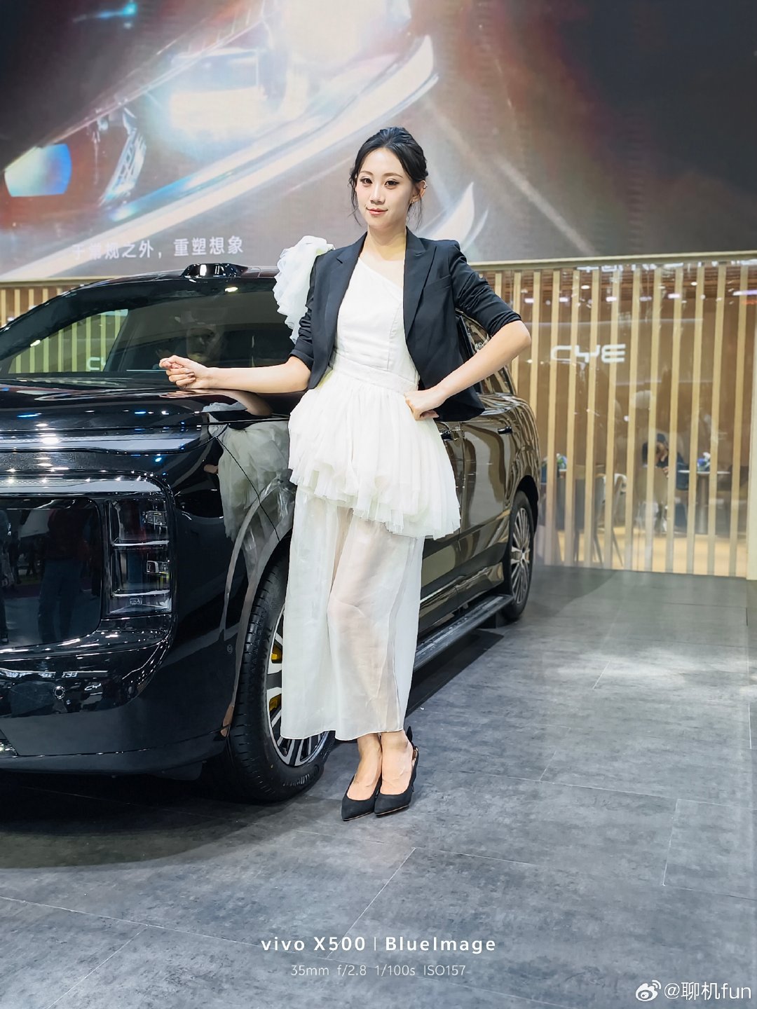 #vivo[超话]# 刚柔交织，是独一份的氛围感。
黑西装的利落，搭配白纱裙的柔软。
在热闹的展厅里，一半沉稳，一半轻盈。
光影落在裙摆上，把这一刻的从容悄悄定格。
#当你有了vivo##人像摄影##vivox500系列# ​