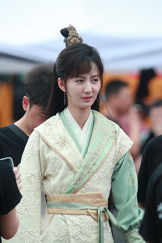 路人镜头下的田曦薇最近真的把反差感玩明白了。
杭州片场的路透里她穿一身剪裁利落的黑西装，露额发型直接把甜妹滤镜撕得干净，眉眼舒展气场拉满，完全是《青风吹又生》里那个在豪门漩涡逆风翻盘的清醒千金林青。结果导演一喊卡，她立马变回原本的样子，站街边和工作人员闲聊，时不时嘟嘴憋笑，碰
