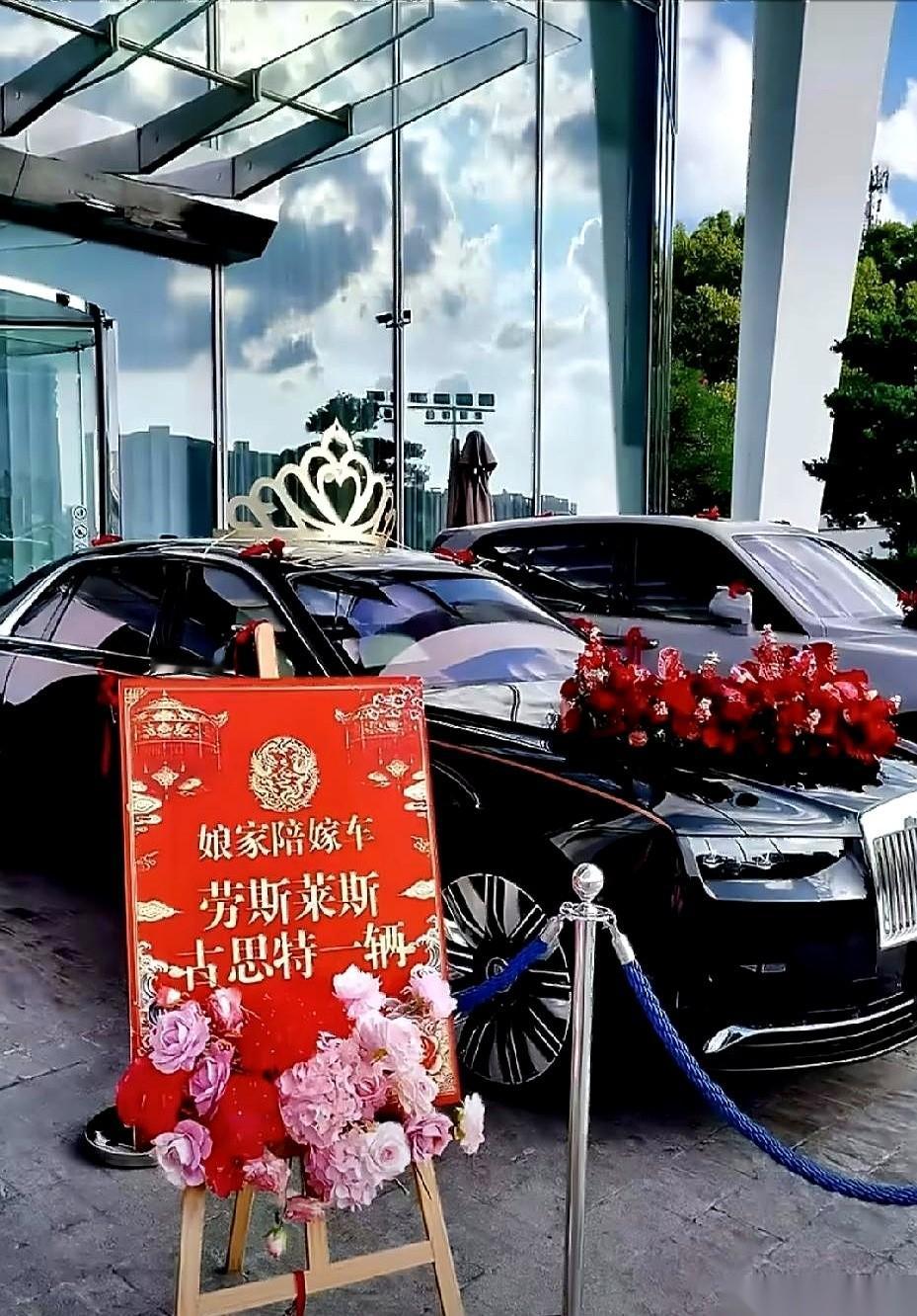 广西河池一场婚礼的娘家陪嫁是两台黑色劳斯莱斯。
一台幻影和一台古斯特顶着皇冠摆件停在酒店门口，旁边专门立着两块红色展示牌宣示这批车的陪嫁身份。
网上围观网友正盯着这两辆千万级别和百万级别车子的后续产权归属进行探讨。
说实话，这排场最扎眼的根本不是那黑漆漆的车身，而是立在旁边那两块红彤彤的牌子。
平时