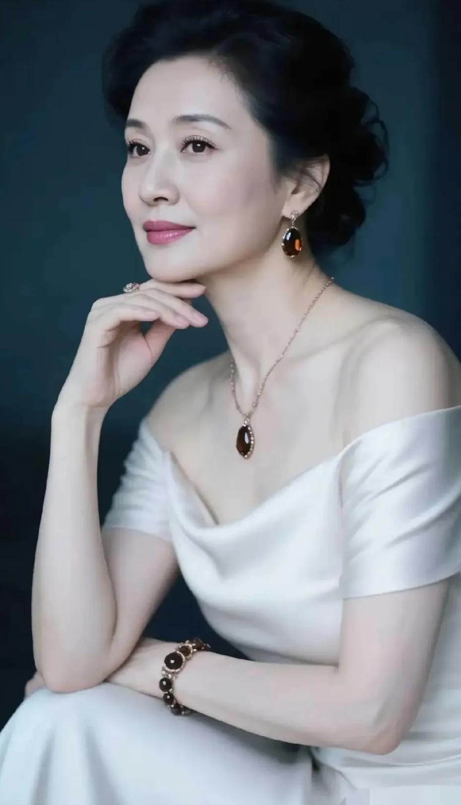 这位女士穿着白色礼服，优雅地坐着。