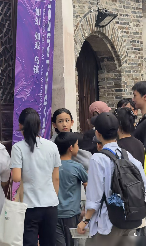 黄磊家老二被堵在乌镇巷子里，一群镜头怼着脸拍，这丫头非但没躲，反而龇牙笑开了。那神气活像黄磊年轻时上综艺耍贫嘴的样，网友直接甩了四个字：长发黄磊。
12岁的黄少艾，跟姐姐黄多多完全是两个路数。多多在旁边给外国剧团当翻译，一口英文又稳又冷，妹妹倒好，扎个卷毛满场窜，见着袁弘还跟人比划鬼脸。孙莉站后头