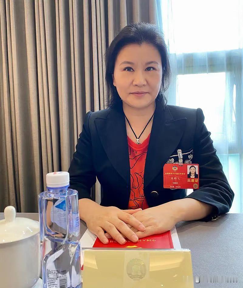 周群飞
不查不知道
她是一直站在风口上，等着猪飞起来

这就是女人的魄力，2026年5月14日，周群飞坐在苹果CEO库克与特斯拉CEO马斯克中间，她凭借实力拿下2大总裁。

23 岁，别人安稳打工，她敢赌上全部。揣着 2 万港币积蓄，带着 8 位亲友，在深圳三室一厅的农民房里开作坊：客厅当车间，卧室