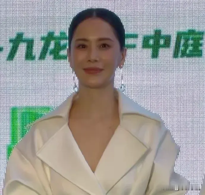 开学后我看到的教育落差海清白衣造型现身线下商业活动状态直接逆龄。她这身大翻领风衣式连衣裙配宽版方扣腰带，腰线掐得倍儿精准，像拿标尺卡出来似的，衬得腰细腿长比例没挑儿，驼色细跟短靴踩得俏利，低盘发搭长款银坠耳饰，皮肤白得发光，实打实的熟女气质范本，整个人大方舒展没半点儿硬凹的违和感，近期线下商务邀