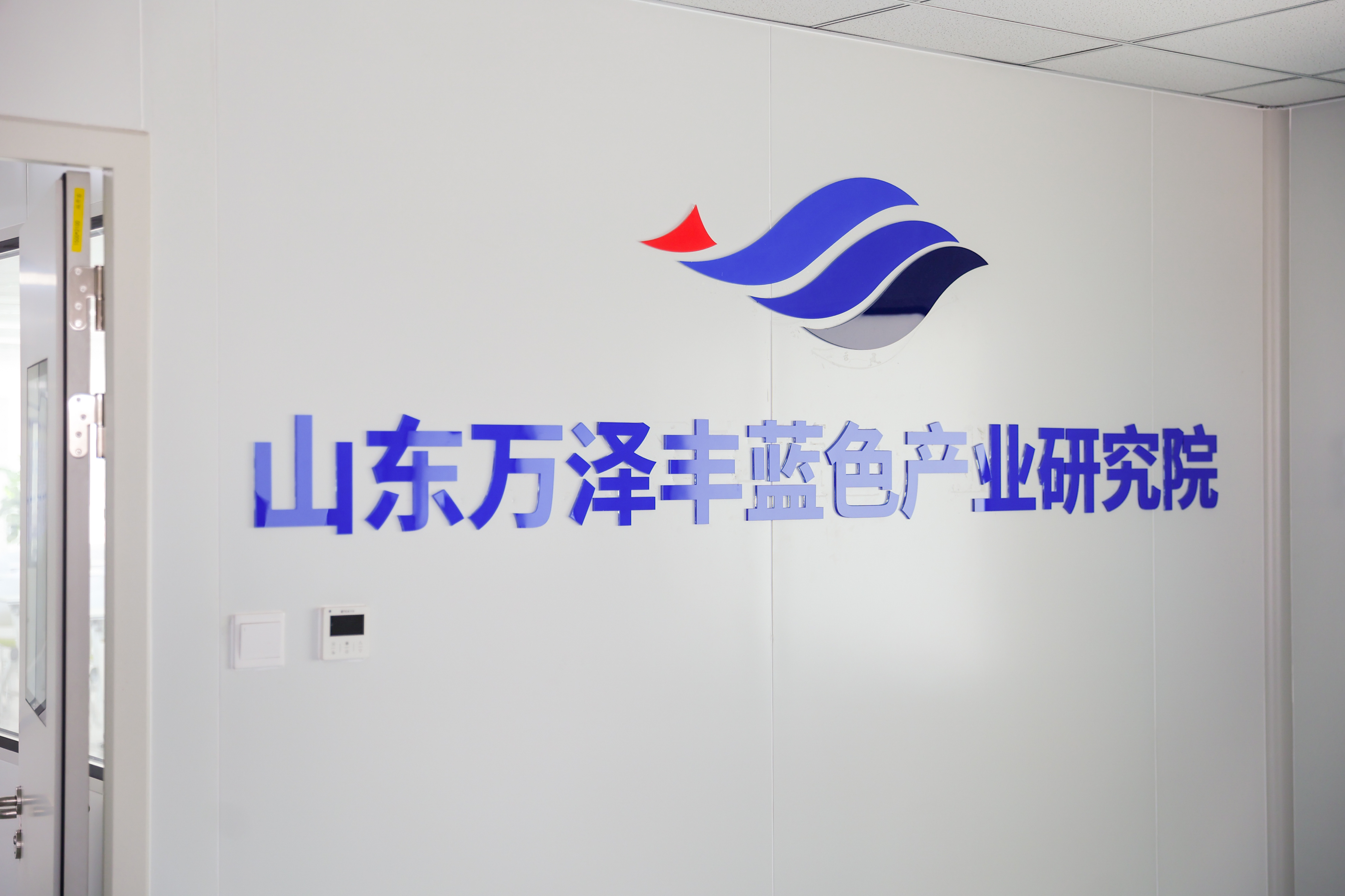 全球首座深远海智能网箱，日照万泽丰如何把三文鱼养到黄海 齐鲁万象新地标兴业看山东监管护航 地标兴业 三文鱼通常生活在高纬度冷水海域，但在日照岚山的黄海冷水团，万泽丰把它养到了低纬度温暖海域。2018年，全球首座深远海全潜式钢结构智能网箱"深蓝一号"在这里建成，背后是中国海洋大学董双林团队整整10年的技术攻关。基地创新构建"陆基育苗驯化+近岸过渡+深远海养成"的陆海接力模式，破解冷水鱼夏季度夏难题。陆上研发中心联动中国海洋大学、黑龙江水产研究所，主攻本土化苗种繁育、病害防控和专用饲料研发，逐步摆脱种源对外依赖。陆地中控平台是整个养殖的大脑。水下传感器、高清摄像和生物监测系统实时回传数据，工作人员通过中控大屏对海上网箱远程管控，实现精准投喂、环境预警和智能巡检。质量管控对接市场监管部门的食用农产品全程溯源体系。从苗种、养殖、投入品到捕捞加工，全链条建立台账；养殖投入品专区存放、登记使用，定期开展药残和水质抽检；加工车间落实进货查验、出厂检验制度，一物一码溯源，每一条三文鱼都可追溯养殖海...