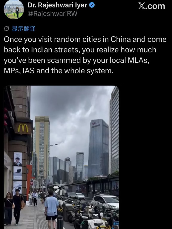 前两天，一位印度女博士在 X 上发了一张她在中国街头随手拍的视频，她的配文极其简单：
	
“一旦你访问了中国那些随机的城市，再回到印度的街头，你就会意识到，你被当地的州议员、国会议员、顶级文官（IAS）以及整个系统诈骗了多久。”
	
请注意她用词里的那个精髓——“随机城市”。
	
这位姐姐拍的绝不是什么上海陆家嘴的玻璃幕墙，也不是北京长安街的宏伟气象。照片里只是一条再普通不过的中国城市街景：
	
路边有一家麦当劳，骑共享单车的小青年，人行道铺着平整的花岗岩砖，旁边整整齐齐的哈啰单车。
	
对于任何一个生活在中国的普通人来说，这样的场景普通到甚至不值得掏出手机点开相机。但对于这位印度姐姐来说，这种“普通”却带来了一场毁灭性的认知地震。
	
为什么她会用“诈骗”这个词？而且一口气把印度的议员和被誉为国家精英的行政文官全部喷了个遍？
	
因为在印度的语境里，“印度文官考试”（UPSC）被捧为全世界最难、最神圣的考试之一。
	
每年上百万人报考，录取率只有几万分之一，能考上 IAS 的人被...