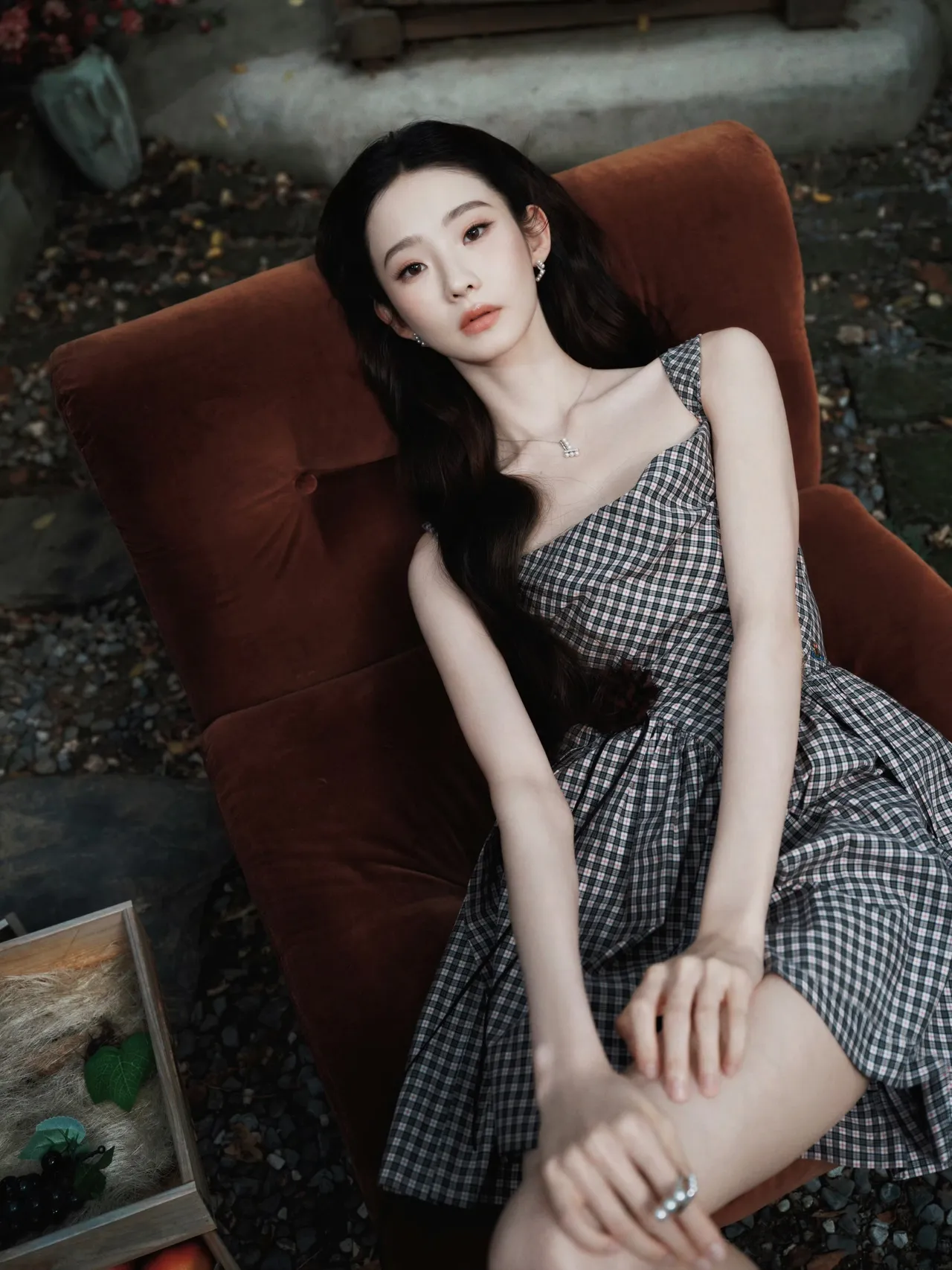 一位姑娘坐在舒适的椅子上，穿着格子裙，神情淡然。 (张艺凡)