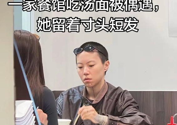 在巴黎街头嗦一碗热气腾腾的面条，一抬头，居然是顶着寸头的窦靖童！这画面，是不是有点太接地气了？
路人镜头里的她，寸头、下巴纹身，一身宽松的中性穿搭，坐在街边大口吃面。酷是真的酷，走在街上回头率绝对拉满。

不过不少网友看完照片嘀咕，说这颜值跟当年仙气飘飘的王菲比，确实差了点意思，五官没那么精致。
但