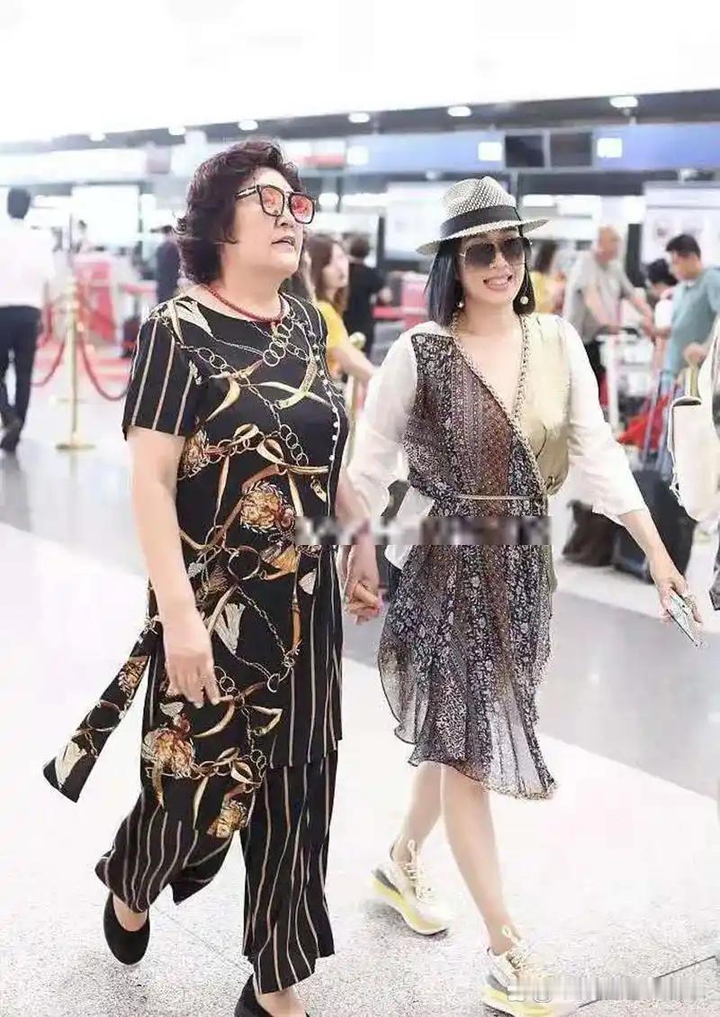 51岁的钟丽缇和61岁的婆婆在一起，钟丽缇打扮得很时尚，看起来特别年轻。婆婆长得比较富态，两人手拉着手亲亲热热的看起来关系很好 ​