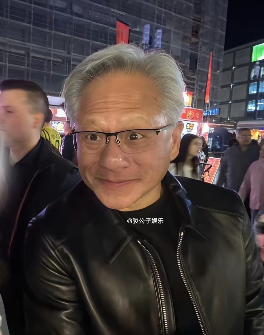 63岁的英伟达总裁黄仁勋现身柏林美食街，穿着标志性的黑皮衣，买了肉饼和烤玉米，站在路边吃得津津有味，毫不在意旁人眼光，非常接地气。
身边虽有多名随行人员，他却毫无大佬架子，和华人留学生合影，笑容幽默，态度很亲和。