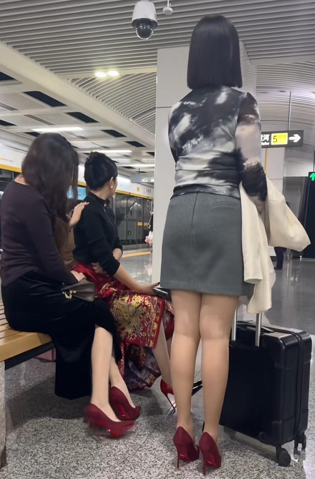 三位穿着红色12公分细高跟女士在候车等待，现实少见引人注目。三个女人一...