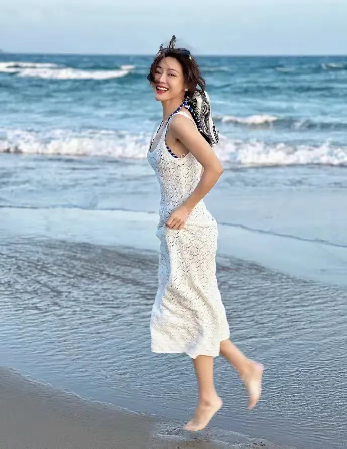 她叫什么，就是传说中的小姨妈吗？白色针织镂空连体长裙，海边赤脚性感美照...