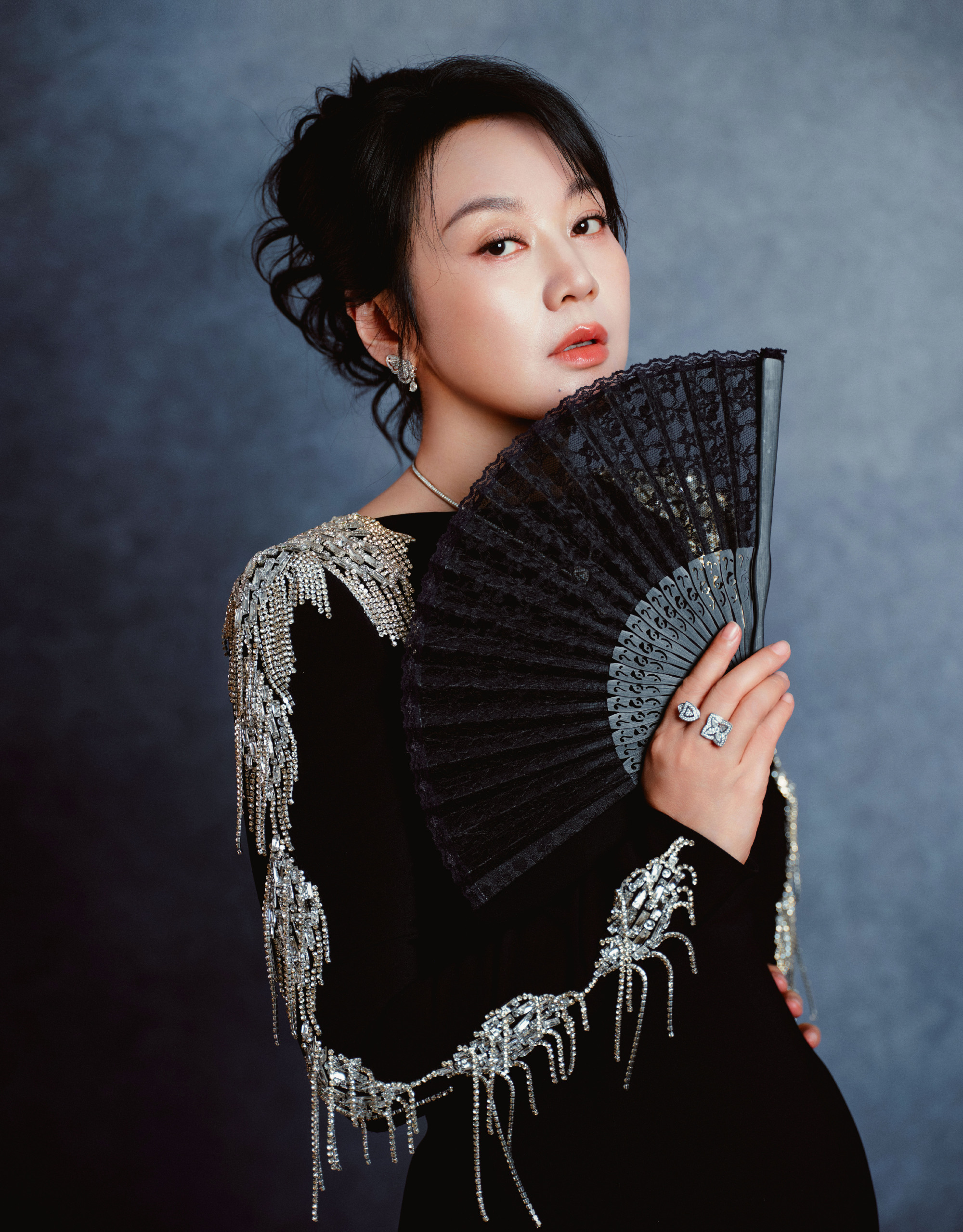 闫妮赴金鹰盛会，黑裙定格光影星光
 
闫妮亮相第33届金鹰奖，一身黑色修身长裙沉稳大气，肩部银白流苏随动作轻晃，精致细节暗藏巧思。她手持黑色折扇，或是轻扶水晶摆件，在灰调布景里从容定格。星光流转，光影相聚，每一个姿态都透着松弛的故事感。沉淀多年的演技赋予她独特魅力，不刻意张扬，却自带强大气场，于镜头