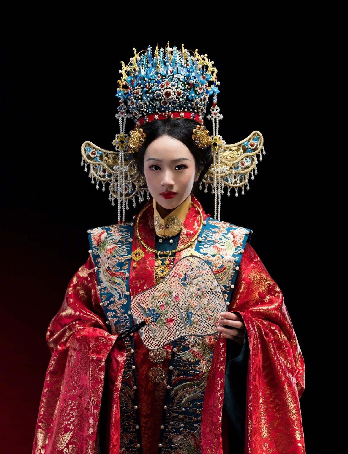 凤冠上的珍珠流苏垂下来，遮住半边眉眼。 十六岁的NeiNei低垂着头，大红织锦缎裹住尚显单薄的肩，指节攥紧粉团扇，像攥着一个还没准备好的春天。
下一秒她换了黑甲。 金冠束发，红缨长枪在掌心转了个向，眼神收拢，冷而亮。 刚才低眉顺眼的新嫁娘不见了，站在那里的是一个横刀立马的人。
这是吴尊带女儿为澳华历
