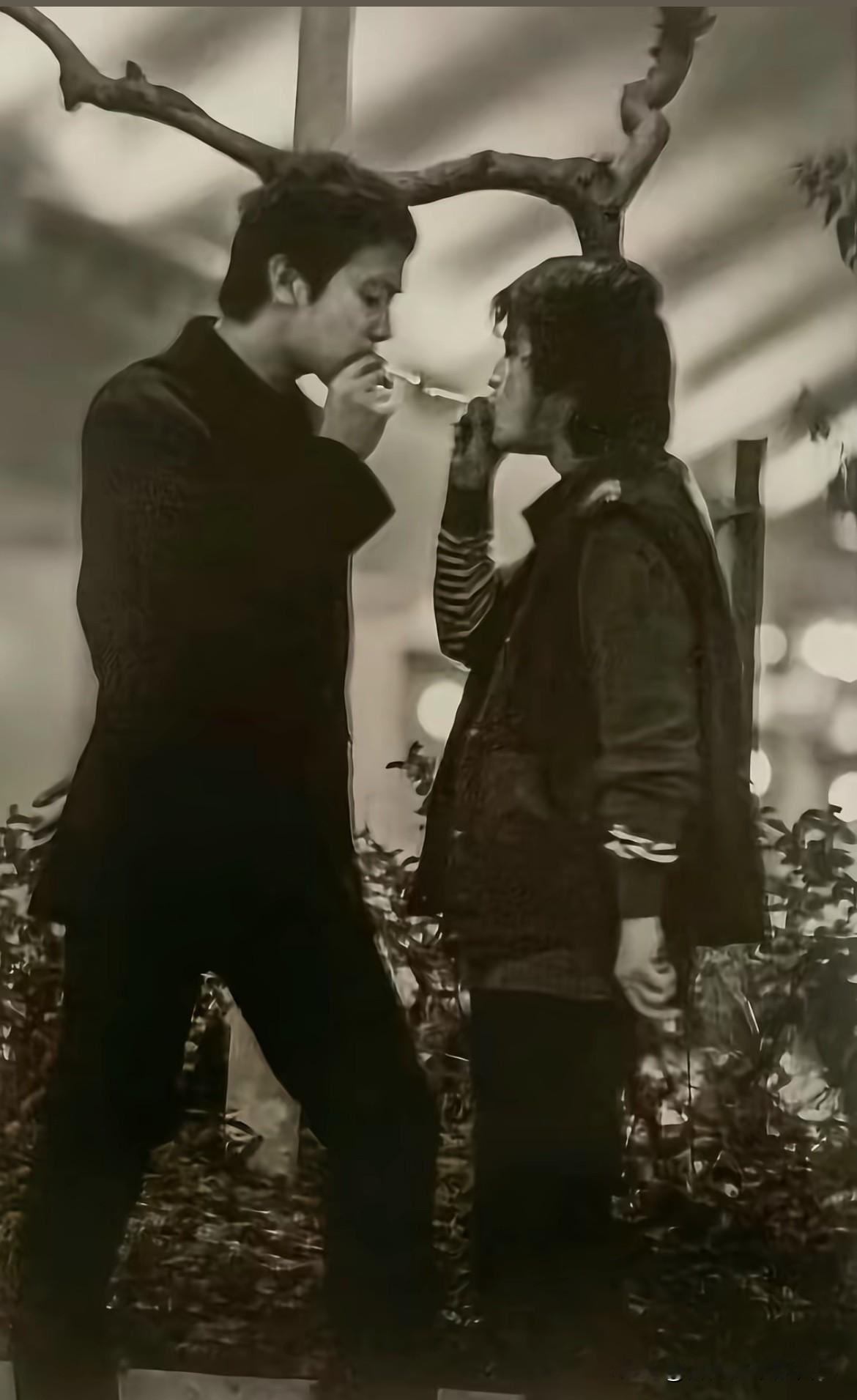 这张照片拍于1994年12月，香港红磡“摇滚中国乐势力”演唱会正式开场前，在后台室外的一处角落拍下的。
左边是窦唯，右边是何勇！二人正凑在一起互相借火点烟，这是当年魔岩三杰传播最广的照片之一，定格了90年代中国摇滚黄金时代的鲜活瞬间。
这么看高原选的视角实在巧妙，窦唯比何勇高出不少，就着这样的高低差