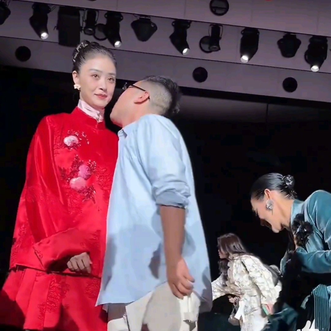 亲脖子。当着所有镜头。蒋欣那个后仰，是本能，骗不了人。

第一遍光看她脸了，第二遍才注意到身体的动作。MESSENTIAL大秀合影环节，品牌主理人马凯凑过去的瞬间，蒋欣整个人猛地往后一缩，嘴里“啊”了一声，手抬起来推了一下。就那种完全没过脑子的应激反应，你懂吧，身体比脑子先做了判断：躲。

然后下一