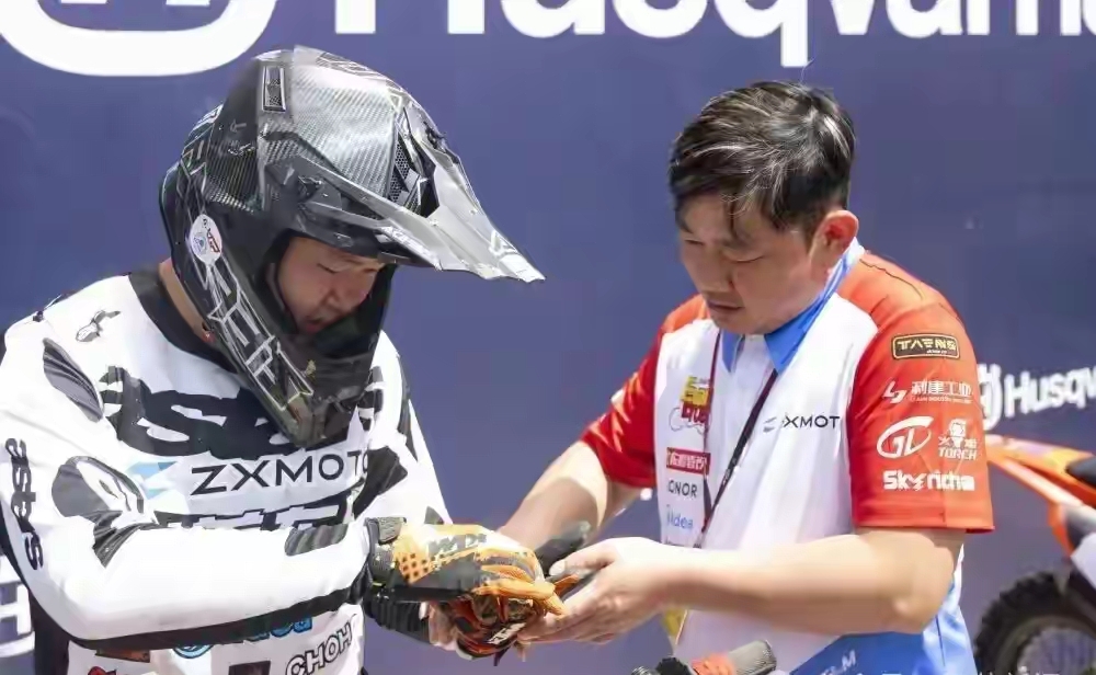 张雪从新疆奔赴上海，只为陪儿子战MXGP

9月12日的上海，世界摩托车越野锦标赛（MXGP）中国站现场，出现了一个熟悉的身影——“张雪机车”创始人张雪。他穿着红白蓝拼接的队服，正俯身给全副武装的儿子张擎天检查装备，动作细致又专注。

这一幕背后，是一段跨越千里的奔赴。就在几天前，张雪本人刚以车手身