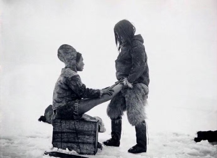 1880-1890年时期，格陵兰岛，因纽特男子用身体温暖妻子的脚 ​​​