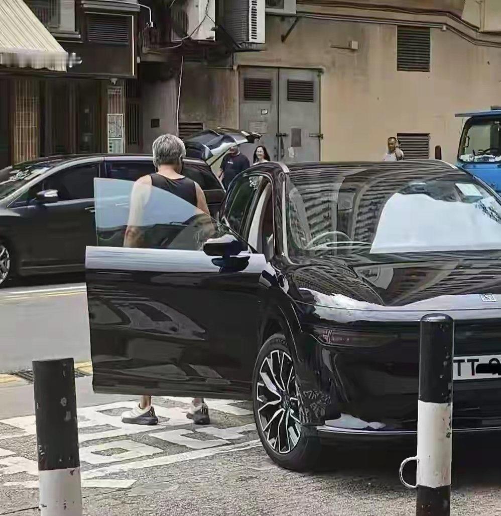 69岁周润发现身香港街头，清晨出门买叉烧，路人随手拍下这一幕。他一身简单黑色背心搭配运动短裤，头发花白，身形依旧利落，精神头十足。身旁停着国产新能源的极氪7X，就随意停在街边，没有保镖簇拥，和普通街坊毫无差别。

说实话真的很感慨，手握几十亿身家，却偏爱市井烟火。没有明星架子，出门就为一口叉烧，车子