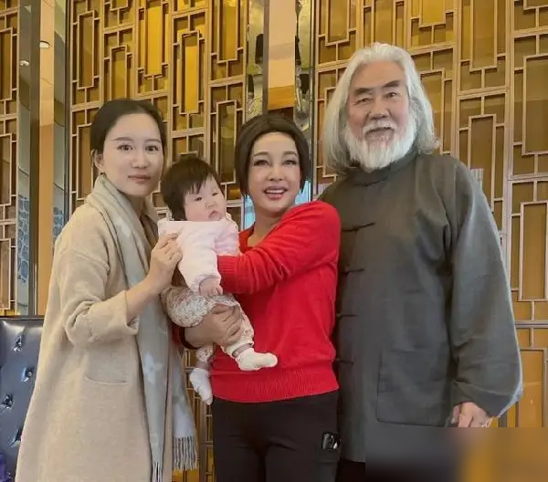 74岁的刘晓庆，抱起张纪中怀里不到一岁的小闺女，孩子扭头就往亲妈杜星霖那边挣。
小手推着，脸别过去，不干。
可你再细看刘晓庆那抱法，一手托颈一手兜屁股，标准得不能再标准。旁边人看着都揪心，怕她累着，她愣是稳稳当当。
杜星霖后来发照片，说庆姐低调朴实，有侠女风范。
这话不虚。当年张纪中筹拍《神