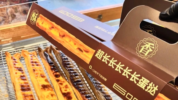 60厘米蛋挞爆火：年轻人终于把“吃甜品”变成了不用讲道理的社交游戏

最近的烘焙圈里，出现了一个完全不讲“正常逻辑”的网红单品：60厘米长的超长蛋挞。
它既没有在口味上做出颠覆性创新，也没有打出“零卡低糖”的健康概念，却硬生生在9月的甜品赛道里杀出重围，让全国数十个城市的年轻人甘愿排队一两个小时，只