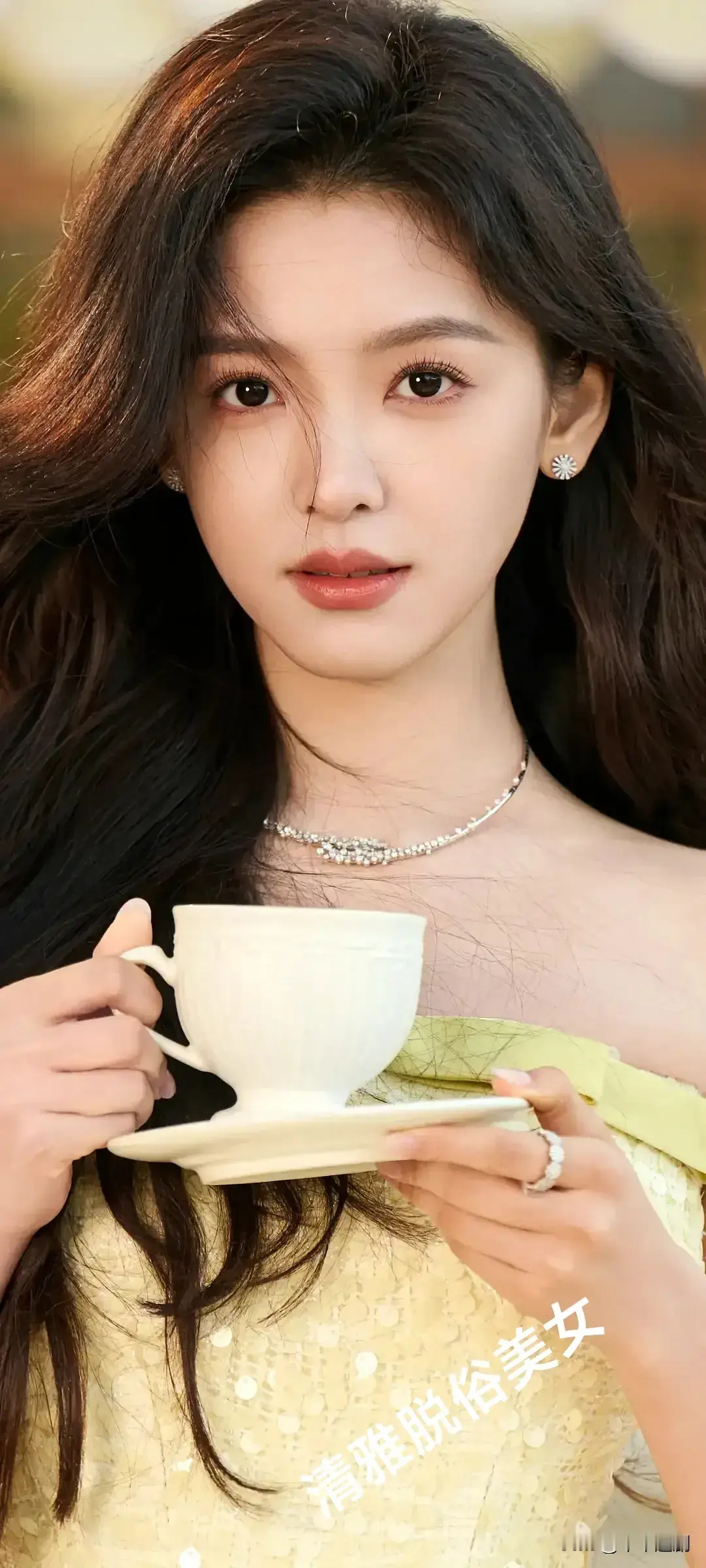 她身着淡黄连衣裙，手持骨瓷杯盏，长发在微风中轻扬。珠宝点缀间，清雅脱...