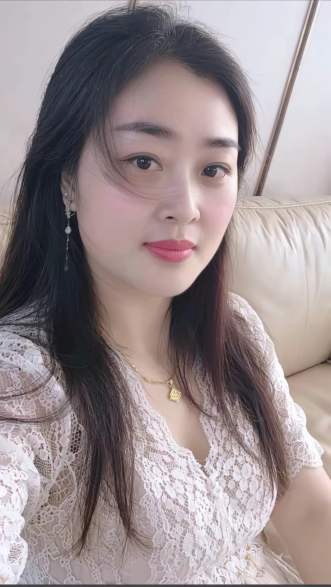 这位美女穿着蕾丝衣服，坐在沙发上。