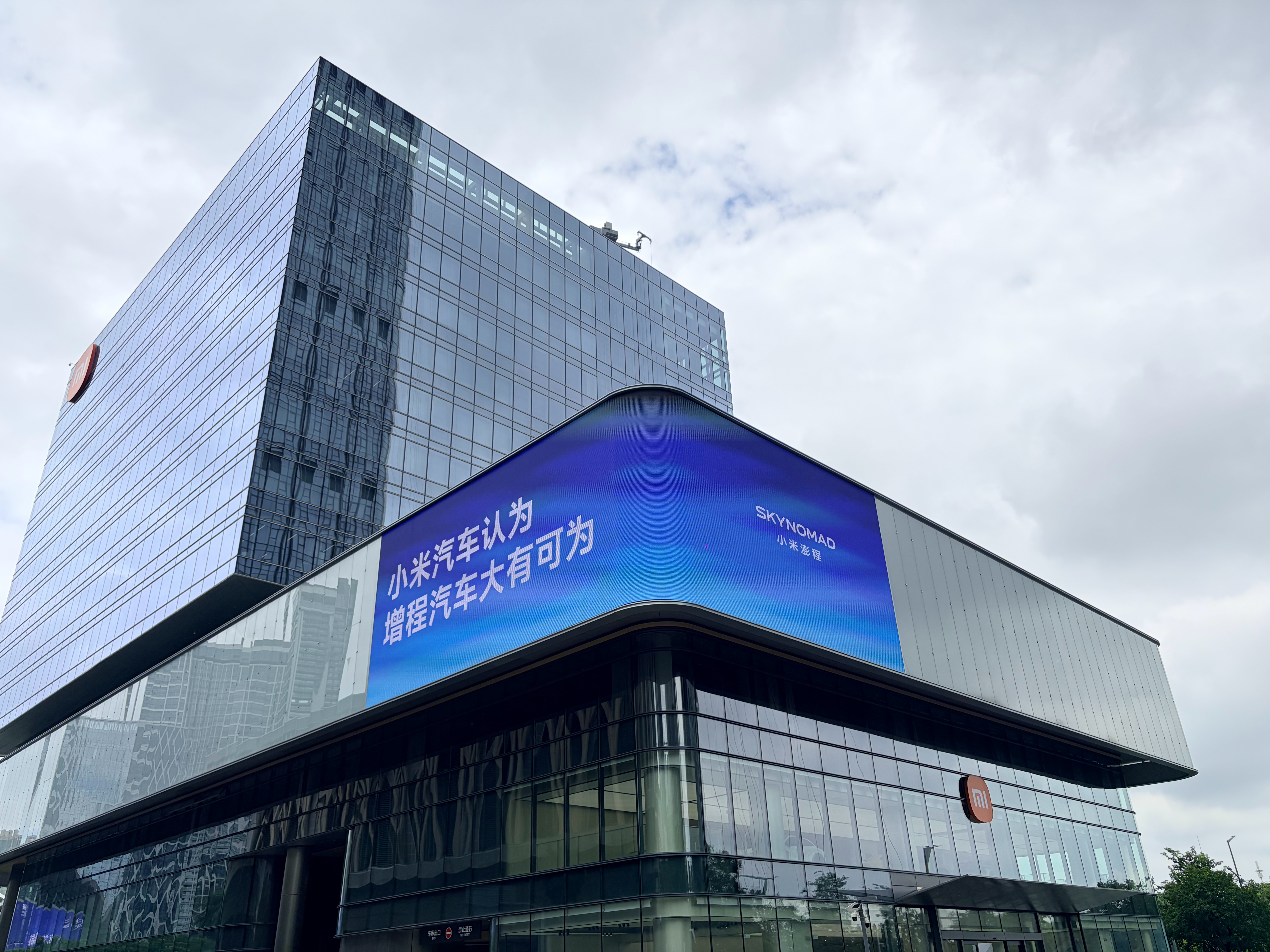参加完上午的活动回家路上路过深圳湾小米国际总部大楼，发现他们外围大屏上不是产品广告，而是写了一句话:小米汽车认为增程大有可为。

感觉这句话份量很重，我专门停车拍了几张图。其实行业吵了好几年增程和纯电的路线之争，到现在还有人觉得增程是过渡方案，是退而求其次的选择。但小米现在这样的表 ​