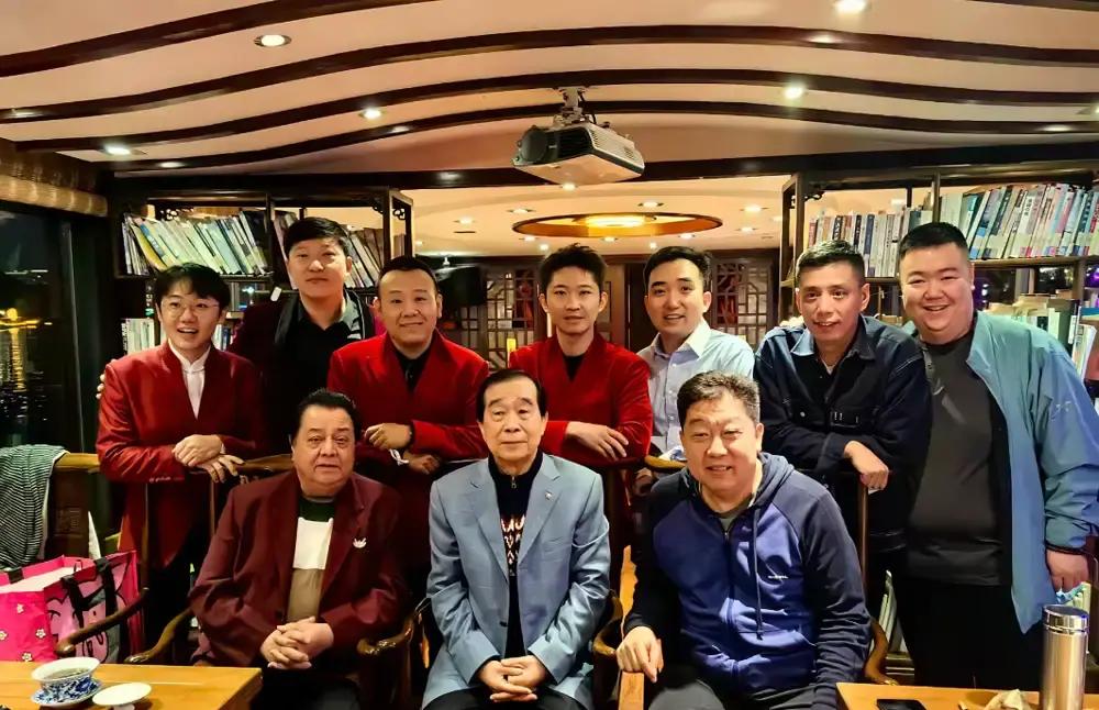 相声圈里排资论辈那一套，在李金斗这个饭局上，算是被贾旭明彻底打破了。
正位空着，左边坐着刘俊杰，右手偏偏坐着辈分低一截的贾旭明。
要是按曲艺界那套论资排辈的死理，李金斗是他亲师叔，刘俊杰也是长辈，贾旭明这种小字辈，大概率只能窝在靠门的位置倒水。
可现实呢？人家偏偏大大方方坐在核心位置，满桌老先
