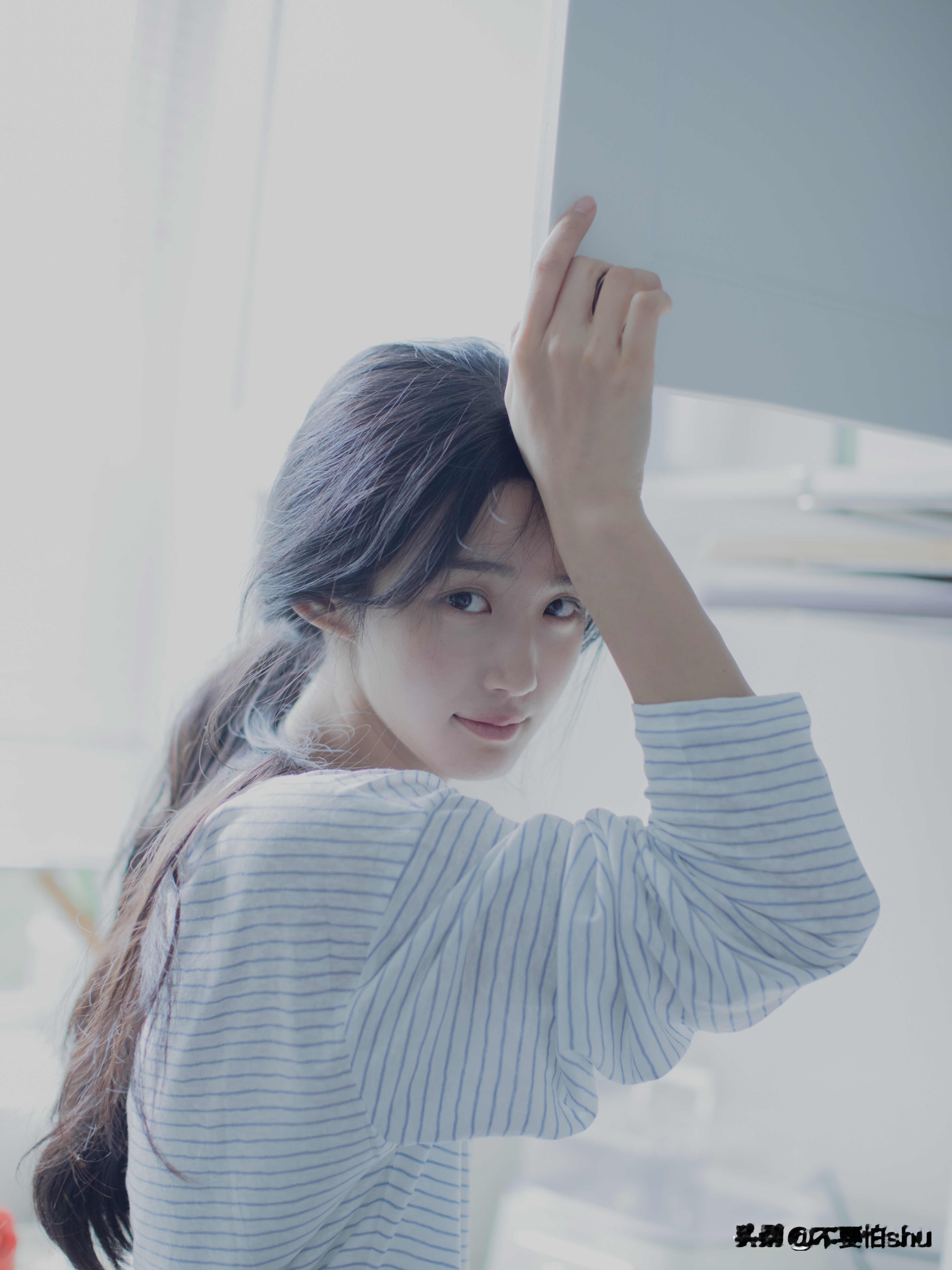 美女在窗边，温柔地抚摸着头发，阳光洒进房间，温馨而美好。[灵光一闪]