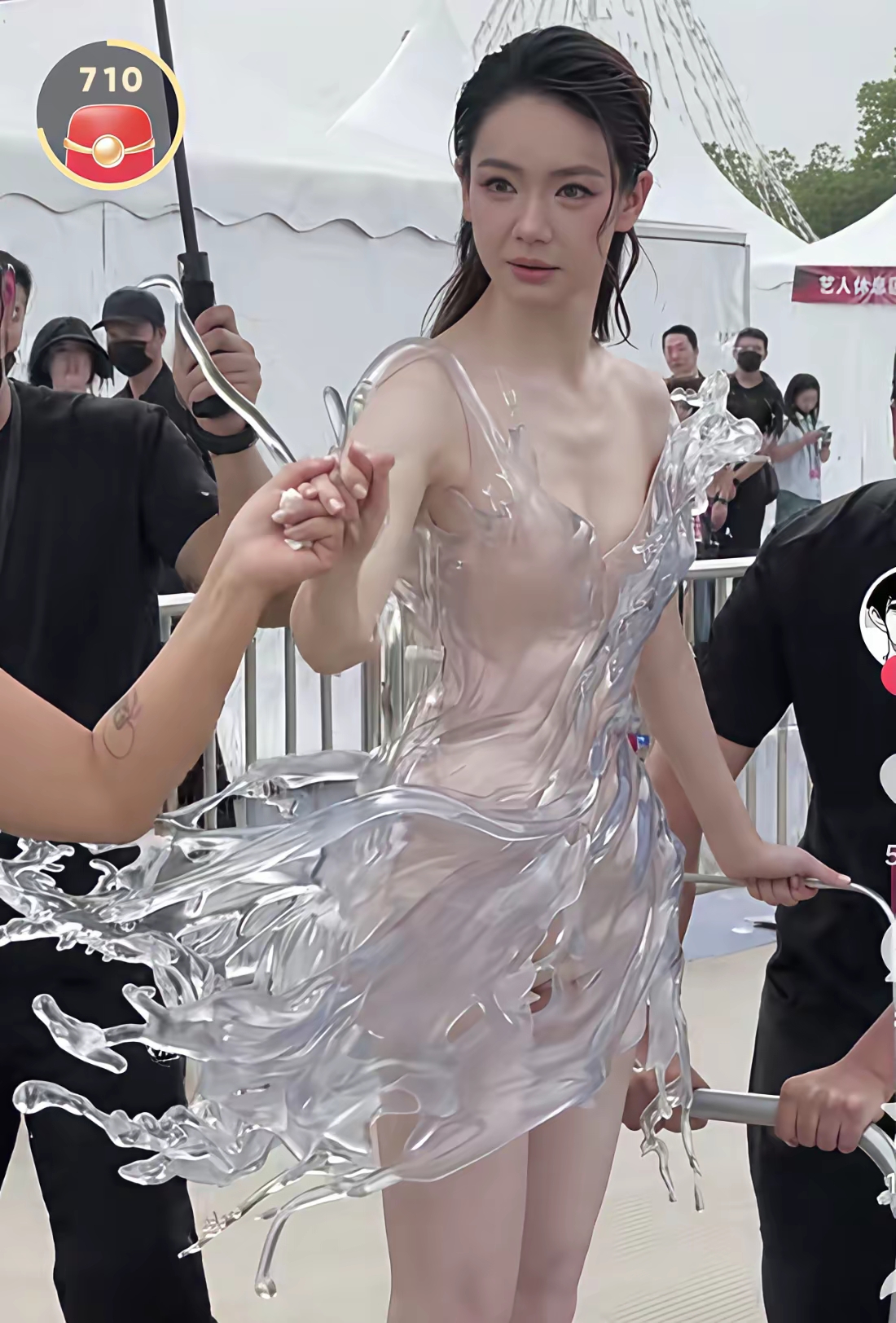 戚薇这件水花礼服，看着像把瞬间凝固的浪花穿在了身上
 
我刷到这组照片的时候，一下子就看呆了。
这不是普通的裙子，是3D打印出来的水花造型，整件足足有16公斤重。难怪戚薇没法自己走路，得靠工作人员推着小推车才能走完红毯。
 
你仔细看，裙摆的造型就像是水突然泼开、瞬间定格住的样子，透明的材质，水珠飞