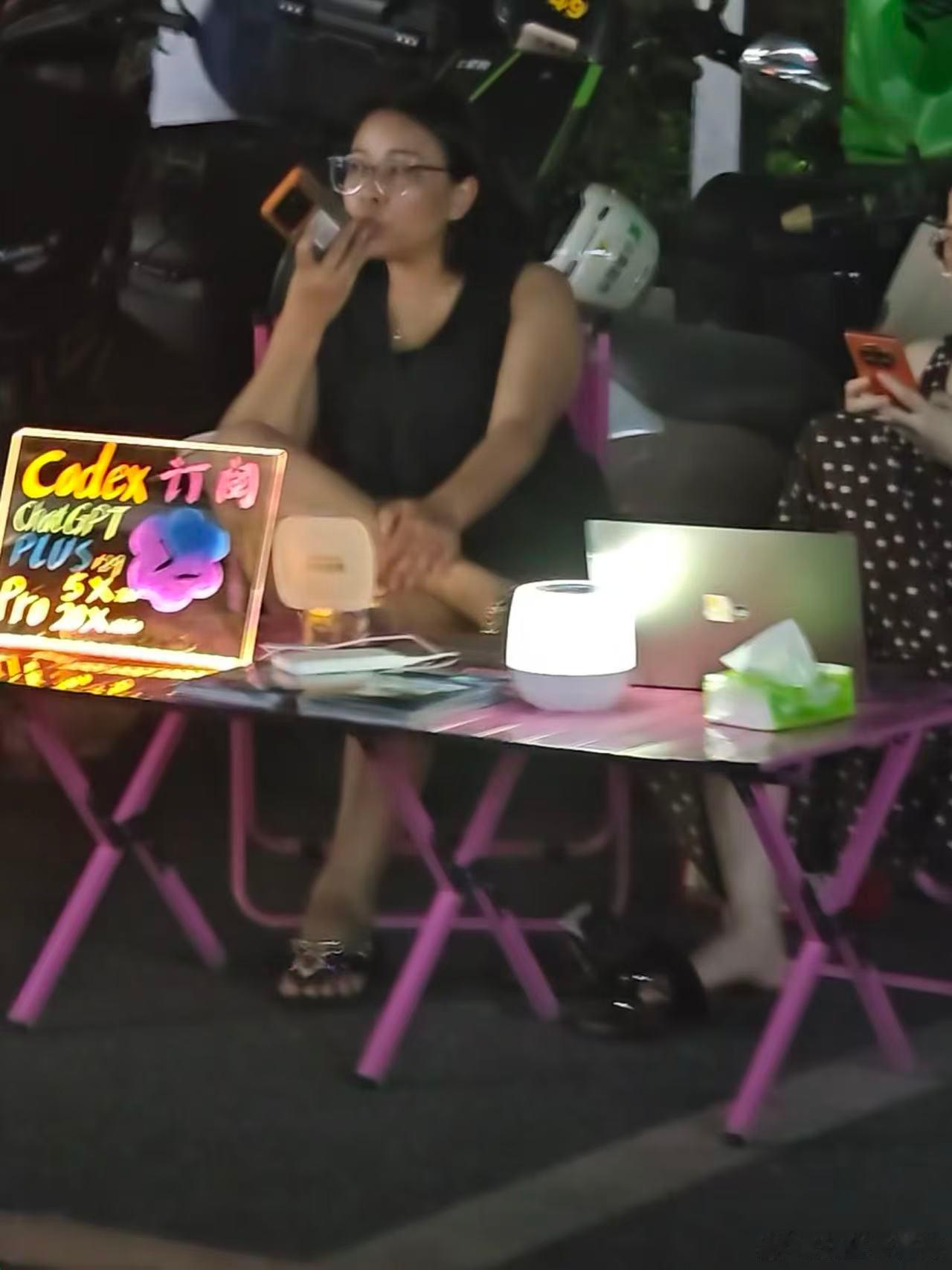 我判断是在深圳广州一带：

1.九月份晚上能够穿短袖，排除西藏青海等部分严寒地区；

2.摊位后面是电动车，锁定到县城及以上地区；

3.摊位的摆放内容十分简朴：codex订阅，说明当地市场有大量需求。锁定到二线及以上城市；

4.没有花哨的彩灯环绕四周，使用醒目的LED发光牌。只放一台干活的电脑，并且 ​